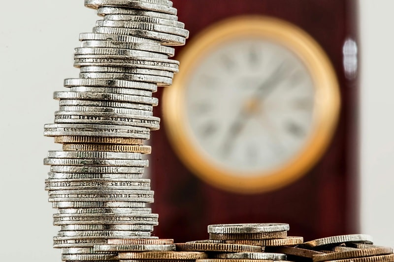 Une pile de monnaie avec une horloge en arrière plan