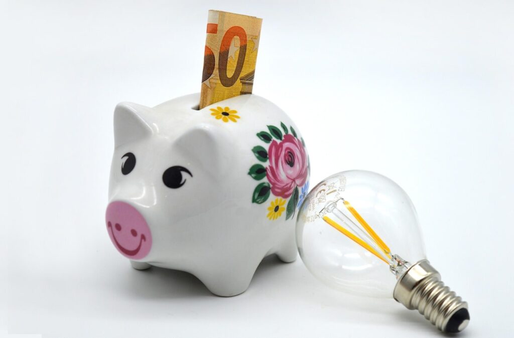 Un billet de banque dans un cochon à côté d'une ampoule électrique pour économiser en électricité