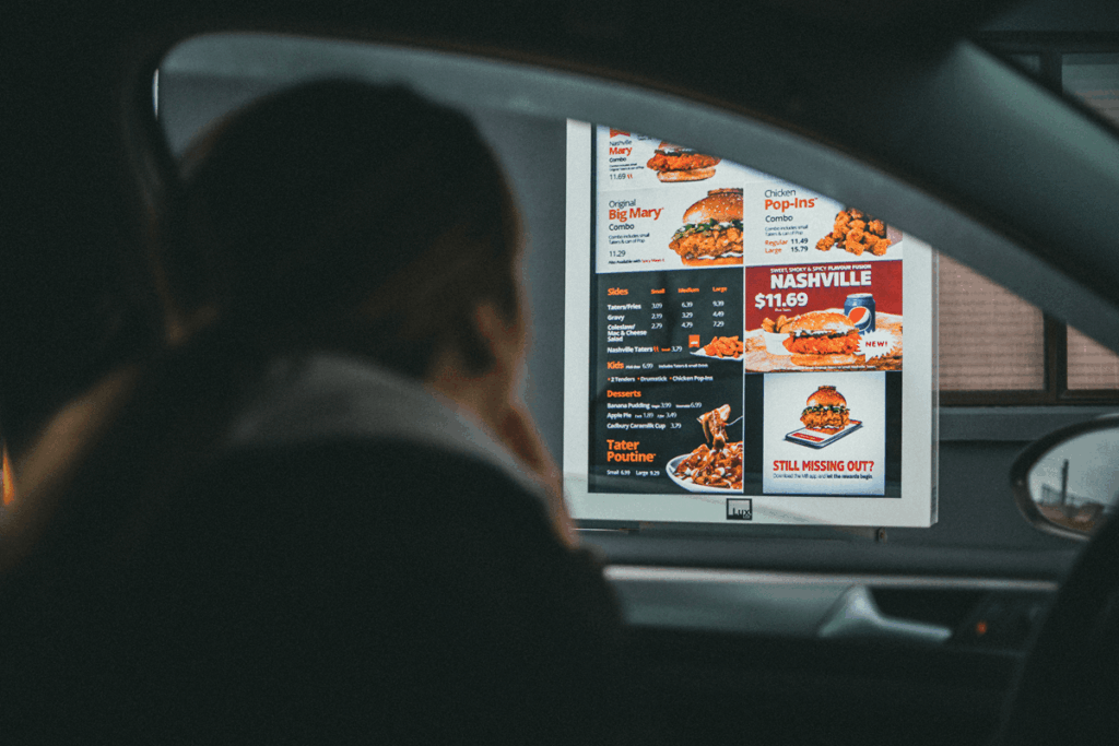 client au service au volant consultant un menu de restaurant rapide de poulet.